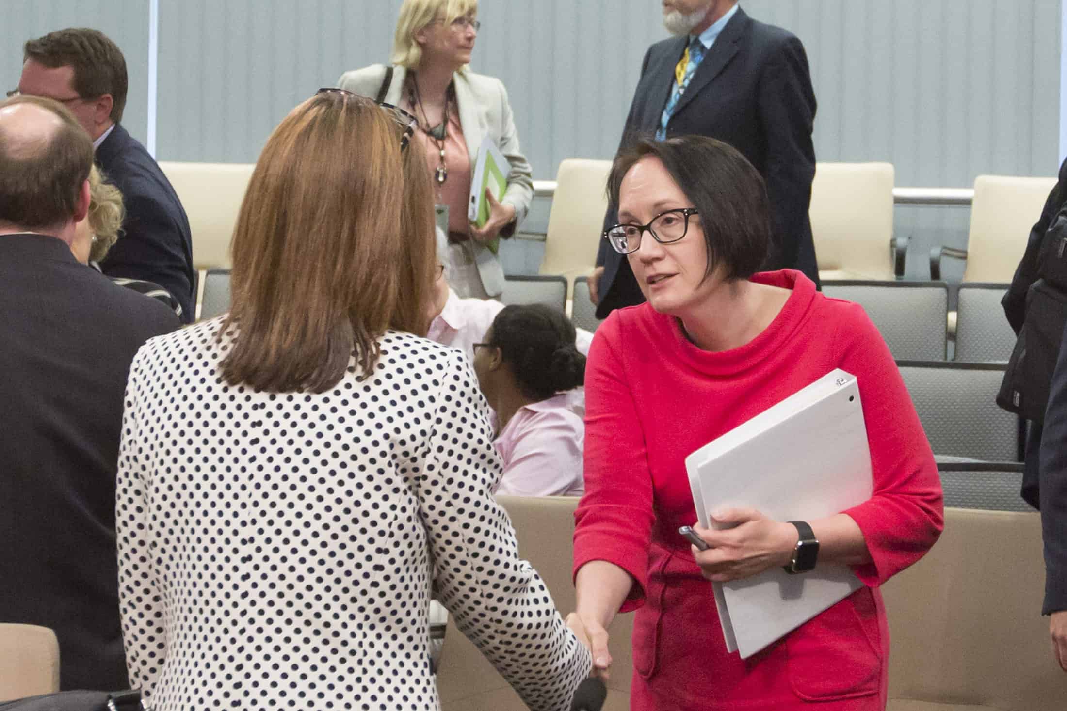 Two women shake hands at an event