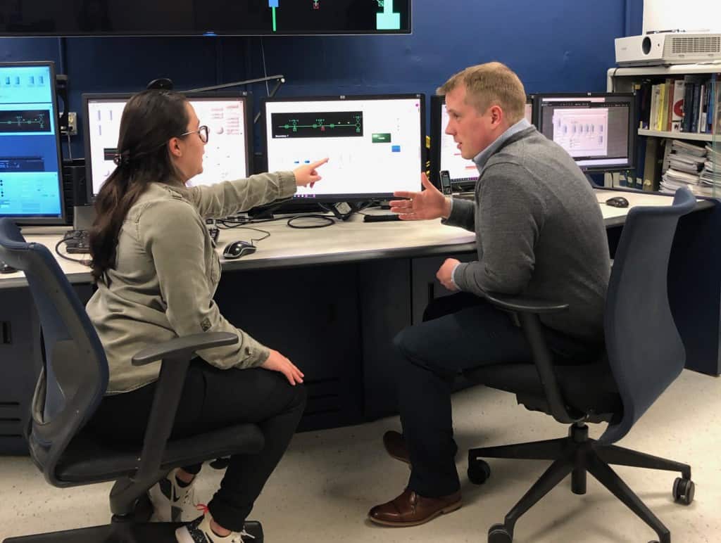 student points at the screen while professor listens