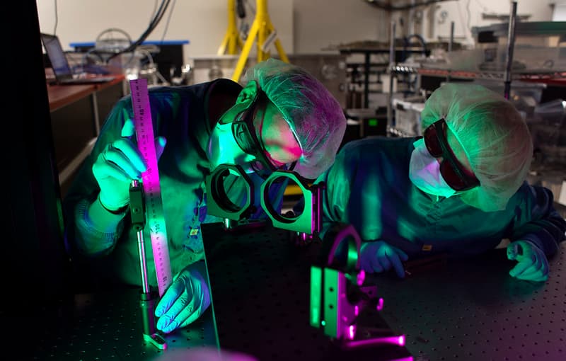 two researchers over a huge box filled with purple and green wires