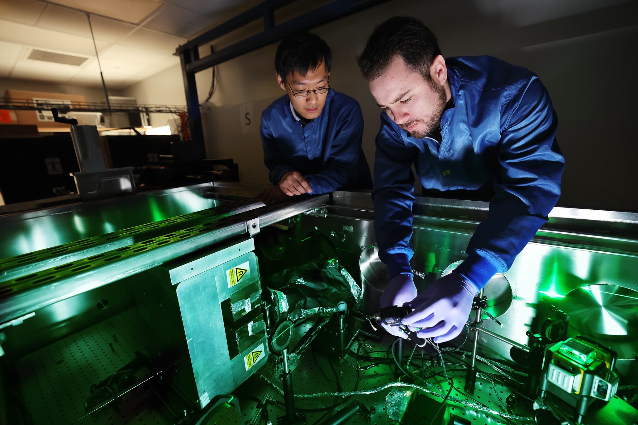 two men work in a green lit laboratory