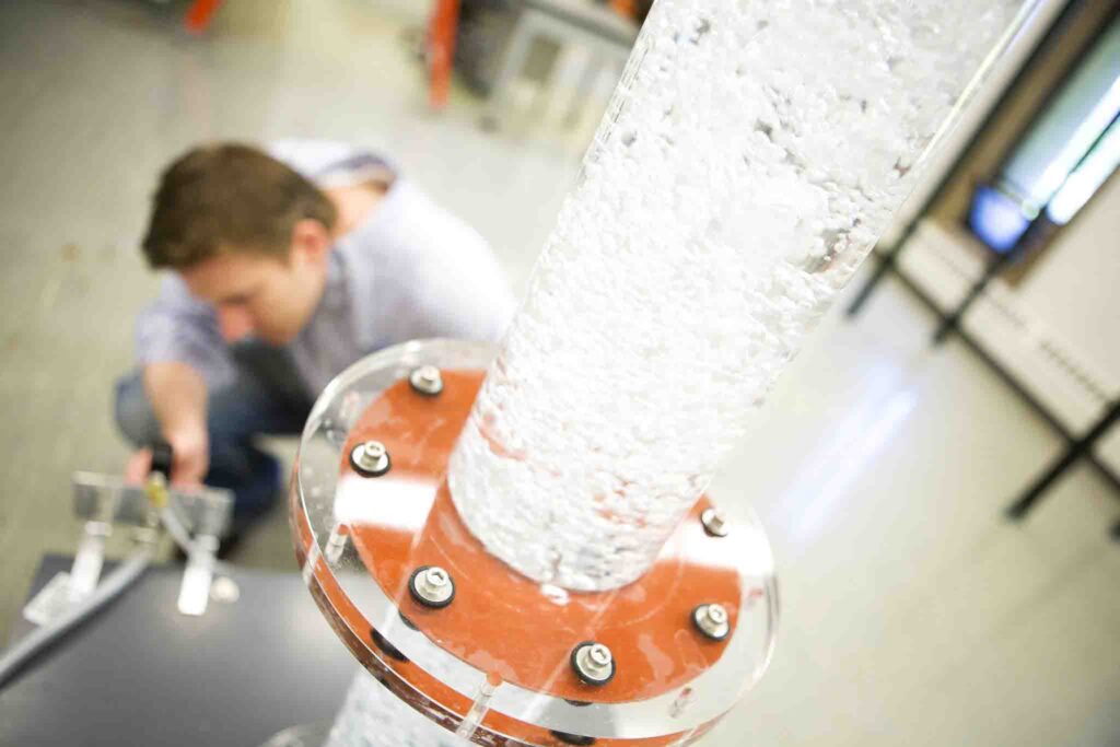 a tube filled with liquid and bubbles with a person in the background