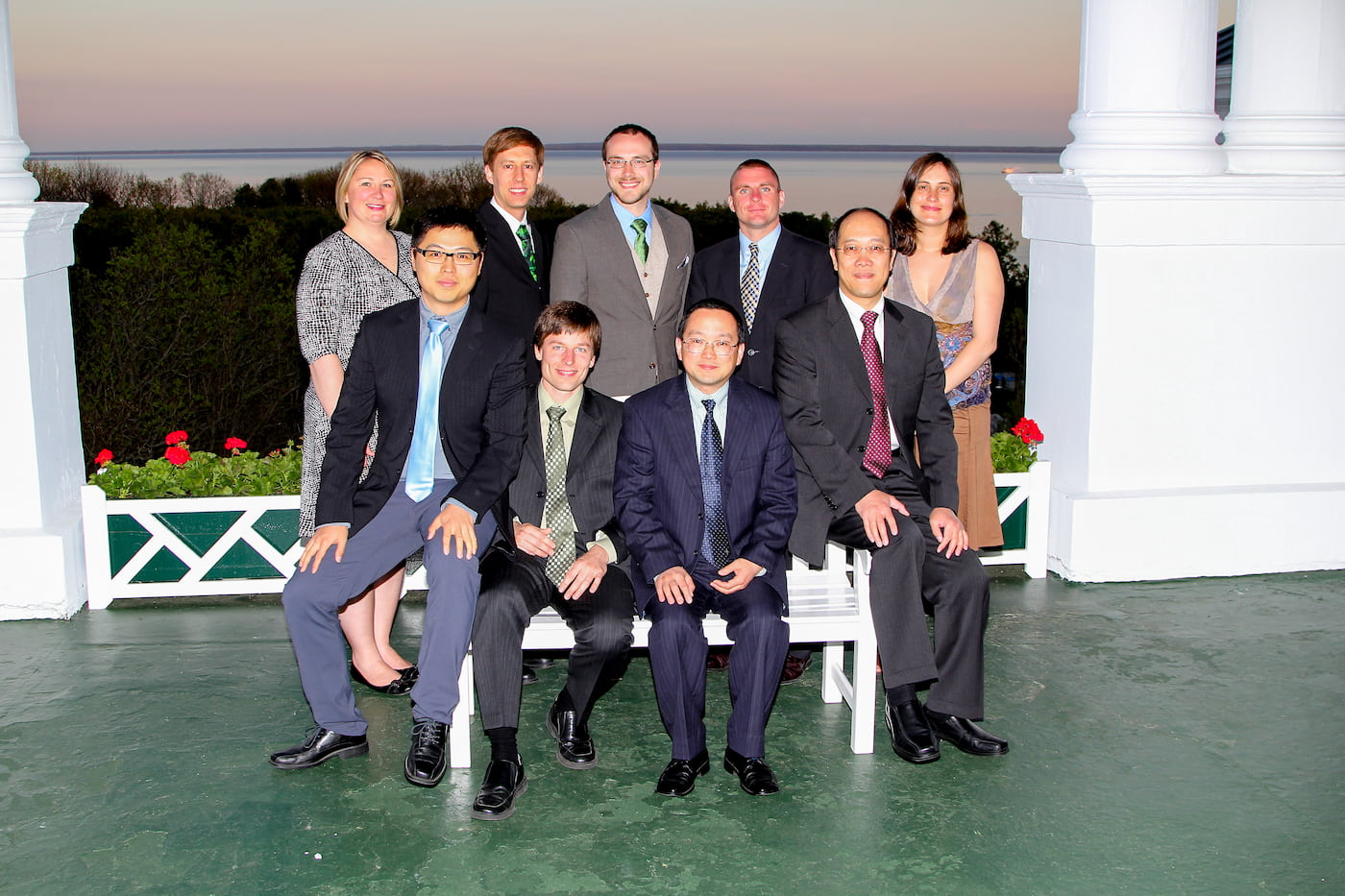 a group of ten people on a large covered porch in front of lake huron at sunset