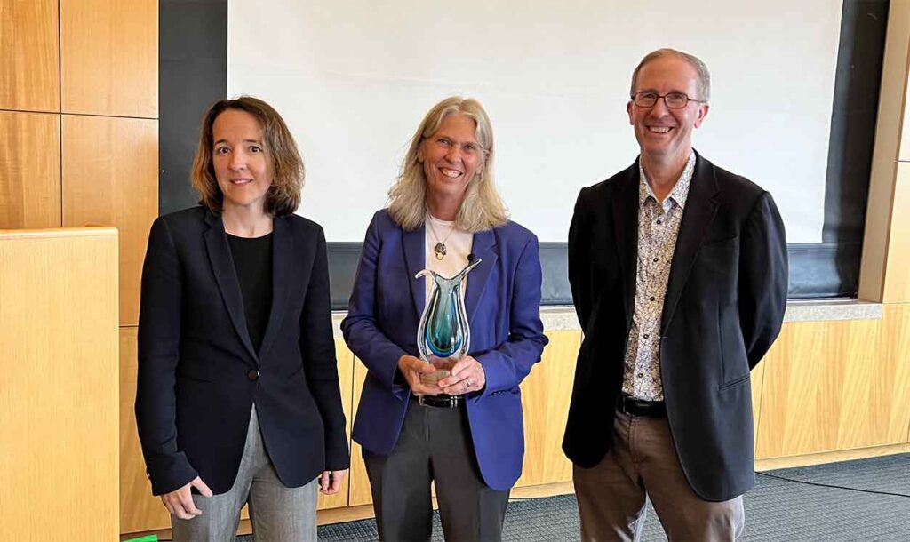 three people, one of them is holding an award