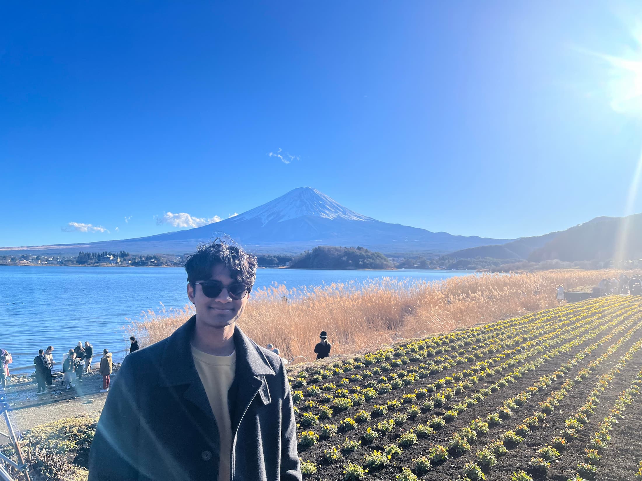 a man in front of crops, a lake, and a volcano