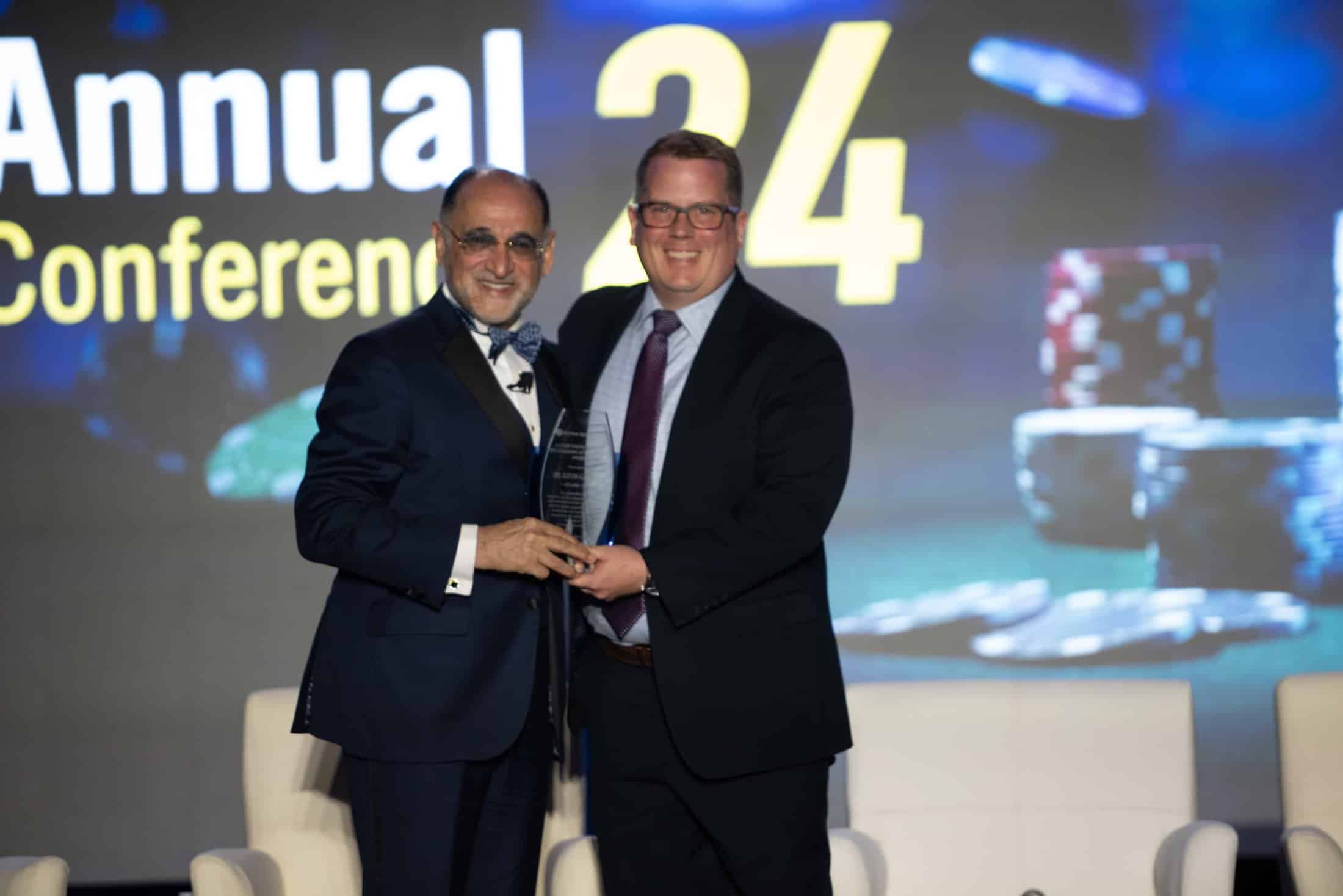 two men in suits, one is presenting an award and the other is receiving