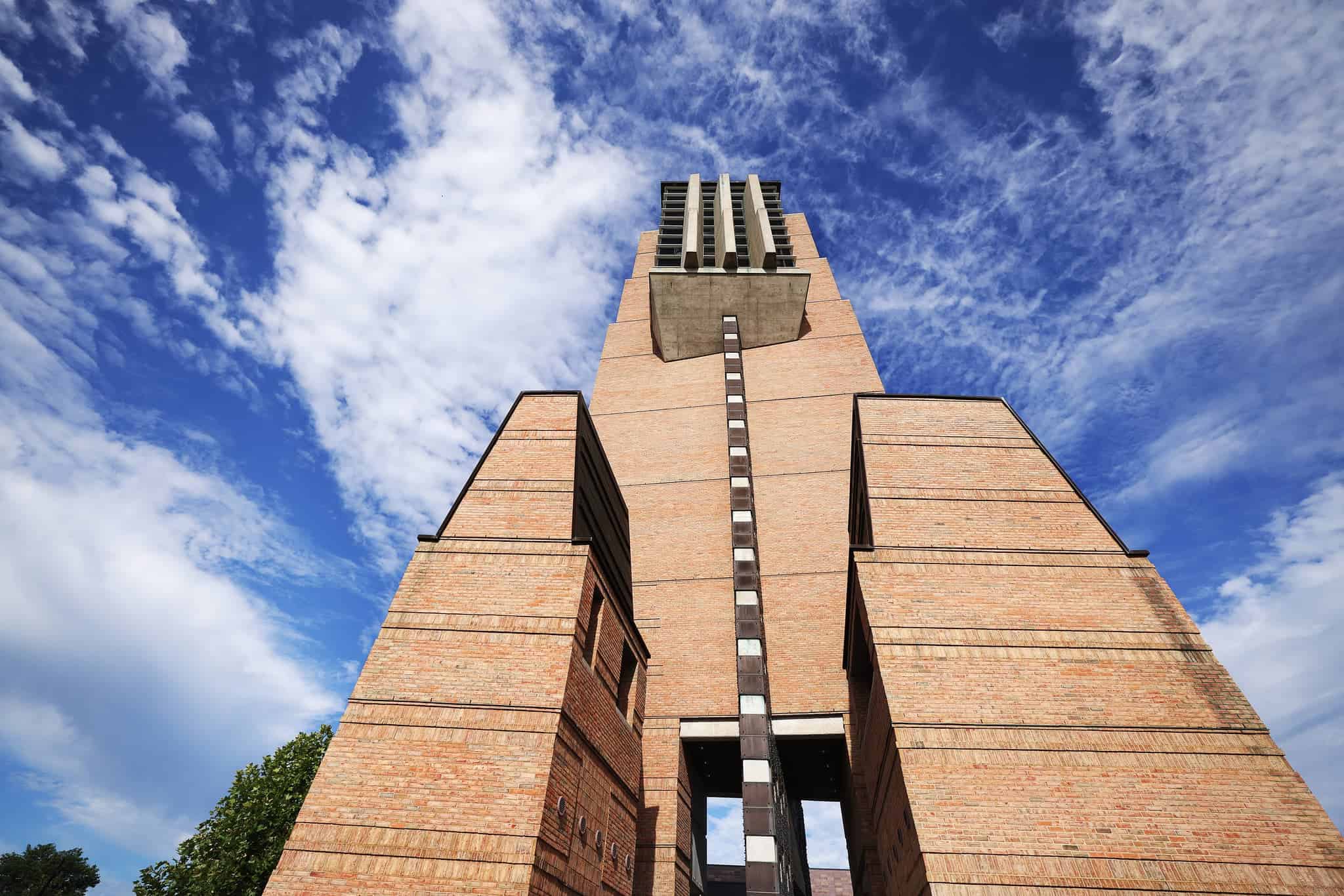 looking up at a tall tower in front of whispy clouds 