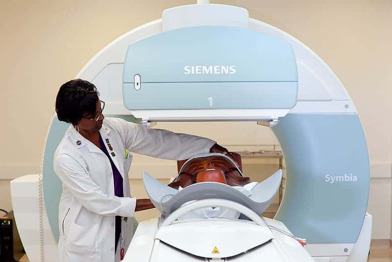 a woman positions a test dummy on a piece of medical equipment 